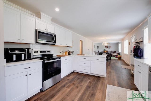 kitchen with stainless steel appliances, a peninsula, open floor plan, white cabinetry, and light countertops