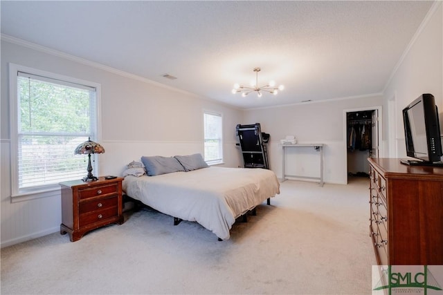 bedroom with light carpet, ornamental molding, a chandelier, and a walk in closet