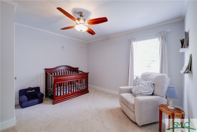carpeted bedroom with ornamental molding, a nursery area, baseboards, and ceiling fan