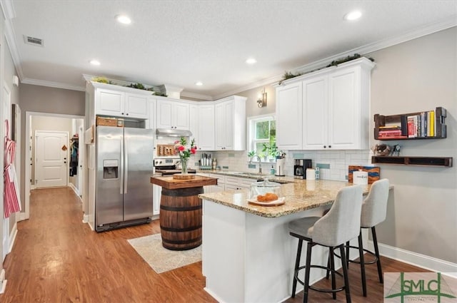 186 Goodman Dr, Midway, GA 31320 - kitchen with appliances with stainless steel finishes, crown molding, under cabinet range hood, a peninsula, and decorative backsplash