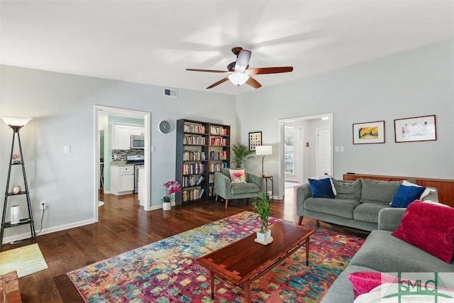 living area featuring wood finished floors, a ceiling fan, and baseboards