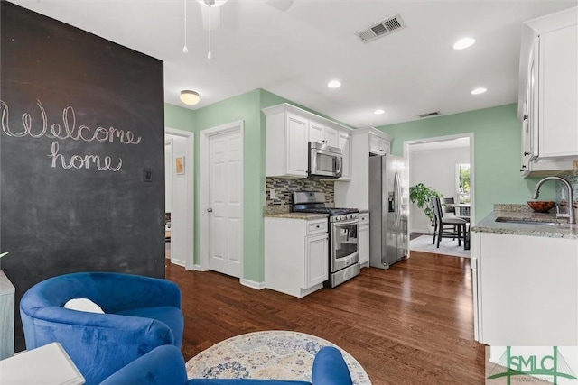 kitchen featuring appliances with stainless steel finishes, a sink, white cabinetry, ceiling fan, and dark wood-type flooring