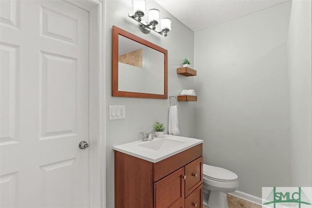 half bath with vanity, baseboards, and toilet