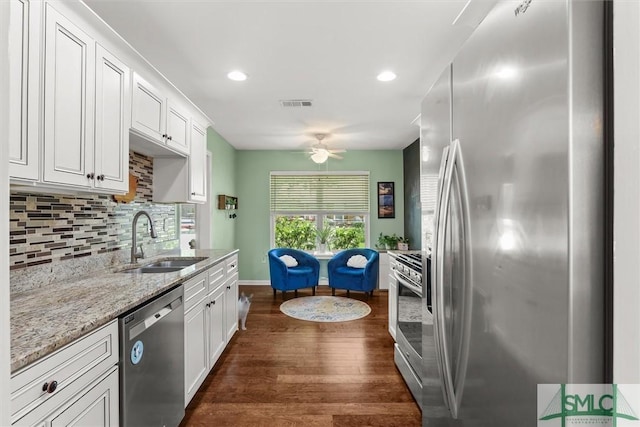 kitchen featuring stainless steel appliances, a sink, dark wood finished floors, a ceiling fan, and backsplash