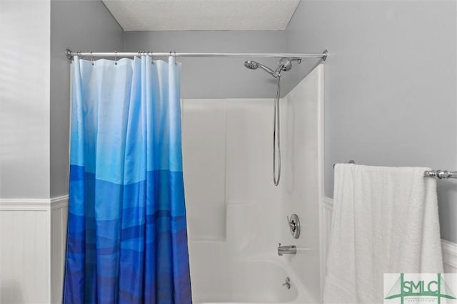 full bath with shower / tub combo with curtain, wainscoting, and a textured ceiling