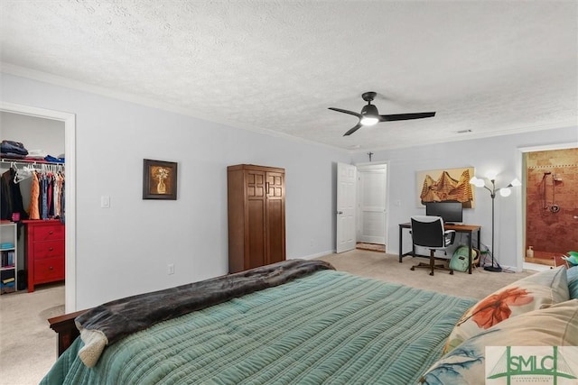 bedroom featuring light colored carpet, a walk in closet, a closet, baseboards, and crown molding