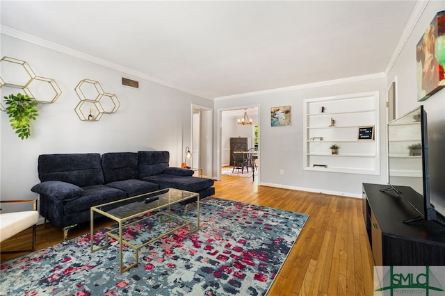 21 Berkley Pl, Savannah, GA 31405 - living room with a chandelier, wood-type flooring, built in shelves, crown molding, and baseboards