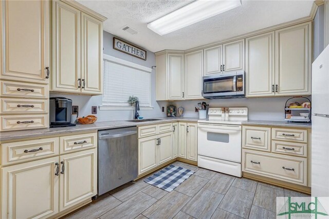 11 Pelican Ct, Richmond Hill, GA 31324 - kitchen with stainless steel appliances, cream cabinetry, a sink, light countertops, and a textured ceiling