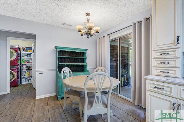 11 Pelican Ct, Richmond Hill, GA 31324 - dining space with a chandelier, stacked washer and clothes dryer, wood finish floors, a textured ceiling, and baseboards