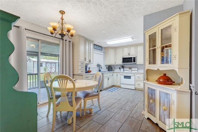 11 Pelican Ct, Richmond Hill, GA 31324 - kitchen featuring white range with electric stovetop, stainless steel microwave, a sink, a chandelier, and a textured ceiling