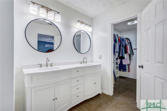 11 Pelican Ct, Richmond Hill, GA 31324 - full bathroom with double vanity, a spacious closet, a textured ceiling, tile patterned flooring, and baseboards
