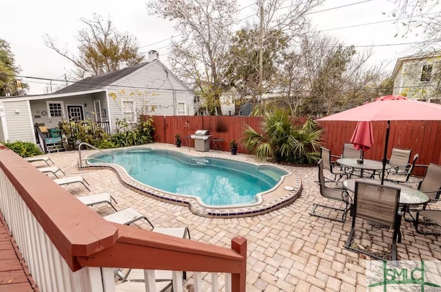 view of swimming pool featuring a patio, a fenced backyard, and outdoor dining area