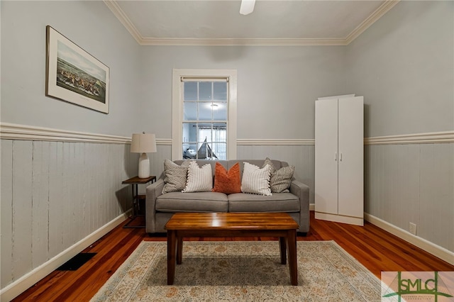 sitting room featuring wood finished floors, ornamental molding, wainscoting, and baseboards