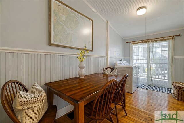 dining area featuring washer / dryer, wainscoting, light wood finished floors, and crown molding