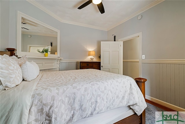 bedroom with a wainscoted wall, wood finished floors, crown molding, and ceiling fan