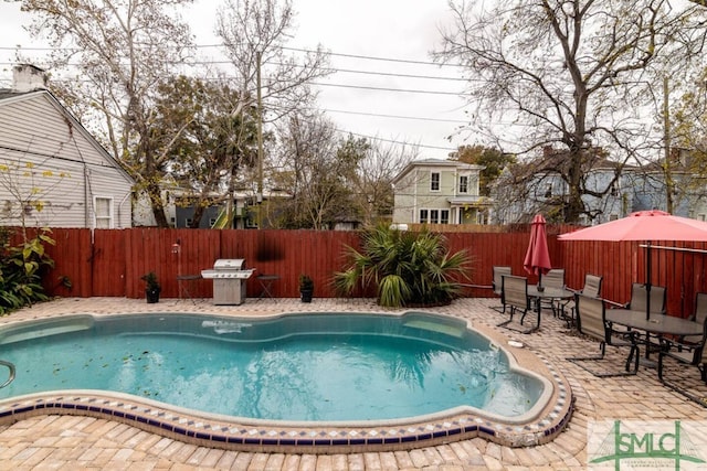 view of pool with a fenced backyard, outdoor dining area, a patio, and a grill