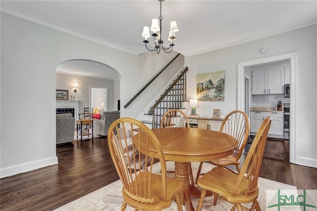 19 E 54th St, Savannah, GA 31405 - dining area with wood finished floors, a chandelier, arched walkways, ornamental molding, and stairs