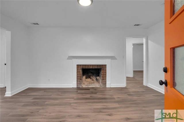 unfurnished living room with wood finished floors, baseboards, and a fireplace