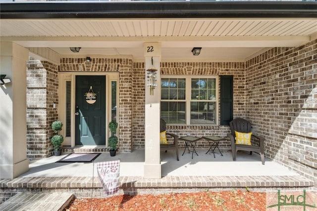 doorway to property featuring brick siding and a porch