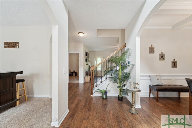 entryway with arched walkways, wood finished floors, and stairway
