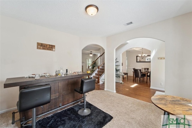 home office with arched walkways, carpet flooring, a chandelier, baseboards, and a bar