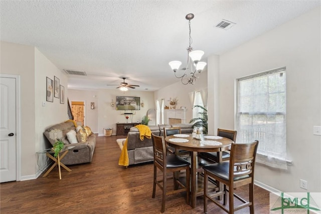 dining room featuring a ceiling fan, dark wood-style floors, a chandelier, a textured ceiling, and baseboards