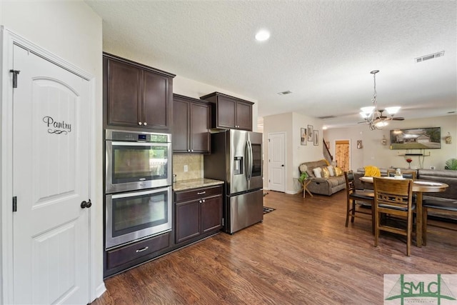 kitchen with appliances with stainless steel finishes, open floor plan, dark brown cabinetry, a textured ceiling, and dark wood finished floors