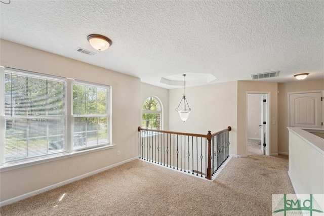 corridor featuring a textured ceiling, carpet flooring, baseboards, and an upstairs landing
