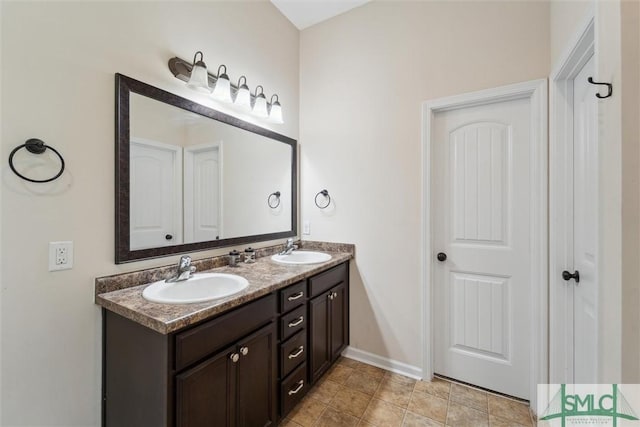 bathroom with double vanity and baseboards