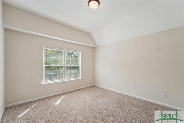 empty room with carpet, vaulted ceiling, and baseboards