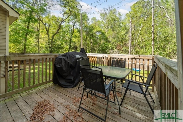 wooden terrace with outdoor dining area and area for grilling