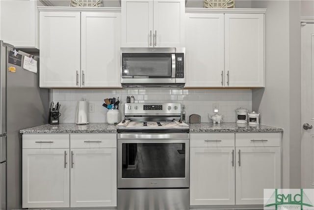 kitchen with stainless steel appliances, decorative backsplash, white cabinets, and light stone countertops