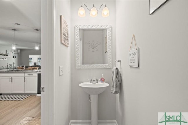 bathroom featuring wood finished floors, baseboards, and a sink