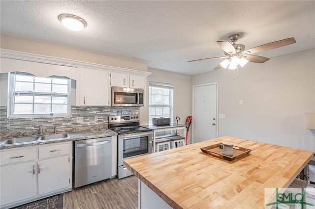 938 Greenbriar Trl, Hinesville, GA 31313 - kitchen with stainless steel appliances, a sink, light wood-style flooring, white cabinets, and butcher block counters
