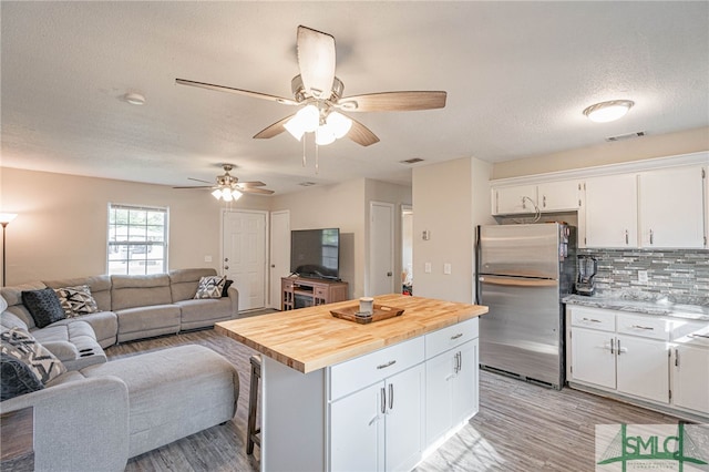 938 Greenbriar Trl, Hinesville, GA 31313 - kitchen featuring freestanding refrigerator, wood counters, white cabinets, light wood-type flooring, and a textured ceiling