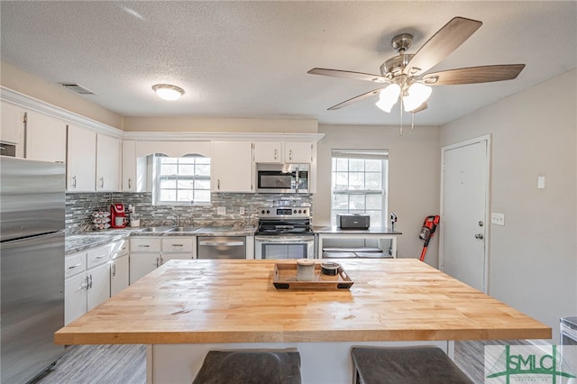 938 Greenbriar Trl, Hinesville, GA 31313 - kitchen with appliances with stainless steel finishes, a kitchen bar, white cabinetry, ceiling fan, and tasteful backsplash