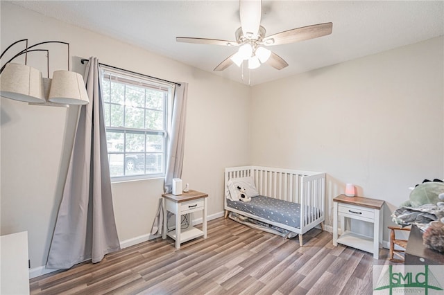 938 Greenbriar Trl, Hinesville, GA 31313 - bedroom with wood finished floors, a crib, ceiling fan, and baseboards