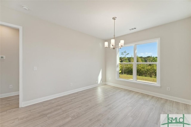 unfurnished room featuring a chandelier, light wood-type flooring, and baseboards