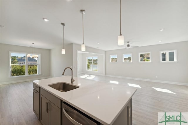 kitchen with a sink, open floor plan, stainless steel dishwasher, baseboards, and recessed lighting