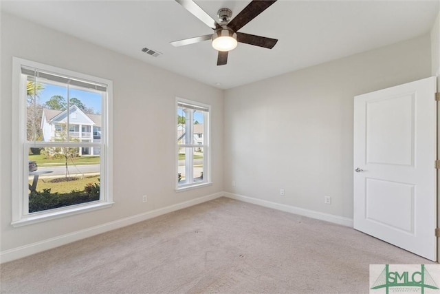 empty room featuring a ceiling fan, baseboards, and light carpet