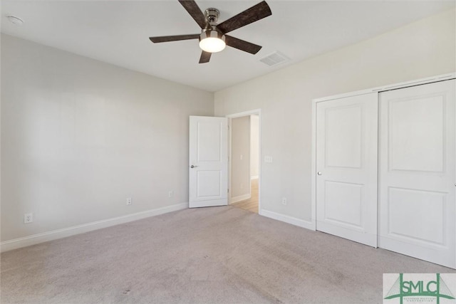 unfurnished bedroom with light colored carpet, baseboards, a closet, and a ceiling fan