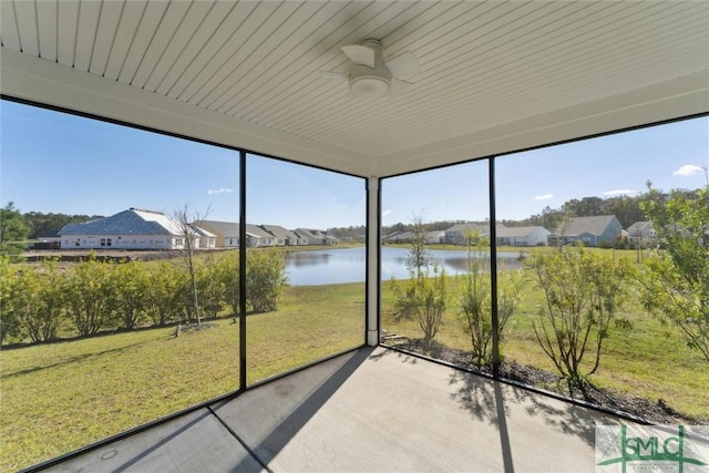 unfurnished sunroom featuring a water view, ceiling fan, a residential view, and plenty of natural light