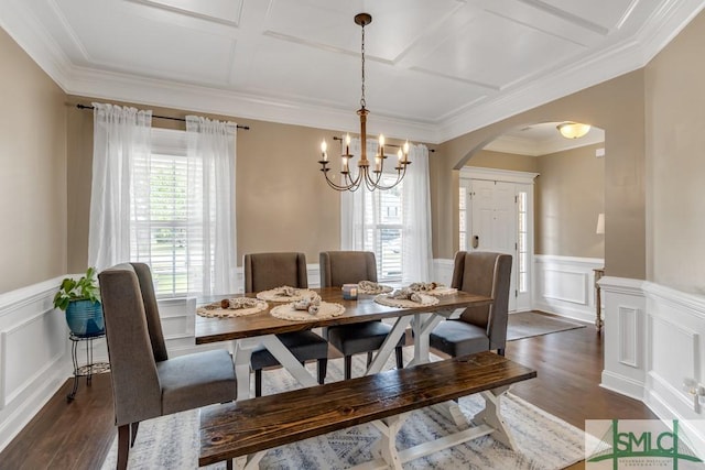 dining space with arched walkways, coffered ceiling, dark wood-style floors, a decorative wall, and wainscoting