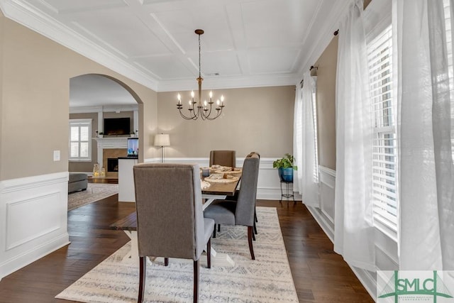 dining room with coffered ceiling, a chandelier, arched walkways, dark wood-type flooring, and a fireplace