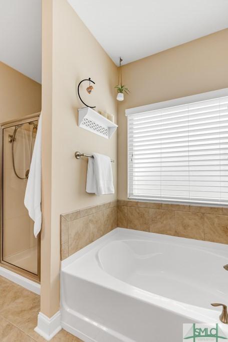 bathroom with a bath, a shower stall, and tile patterned floors