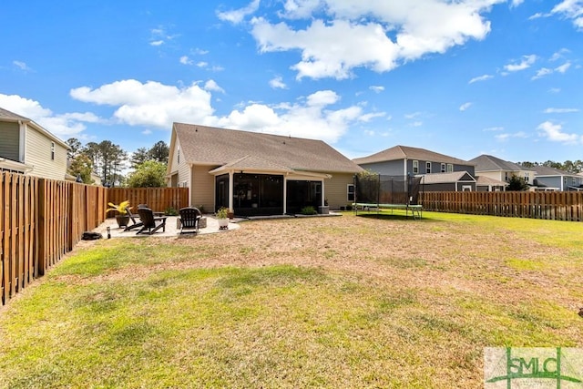 back of house with a trampoline, a sunroom, a fire pit, and a patio area