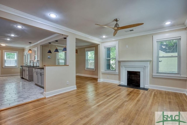417 E 61st St, Savannah, GA 31405 - unfurnished living room with a ceiling fan, baseboards, a sink, a fireplace with flush hearth, and crown molding
