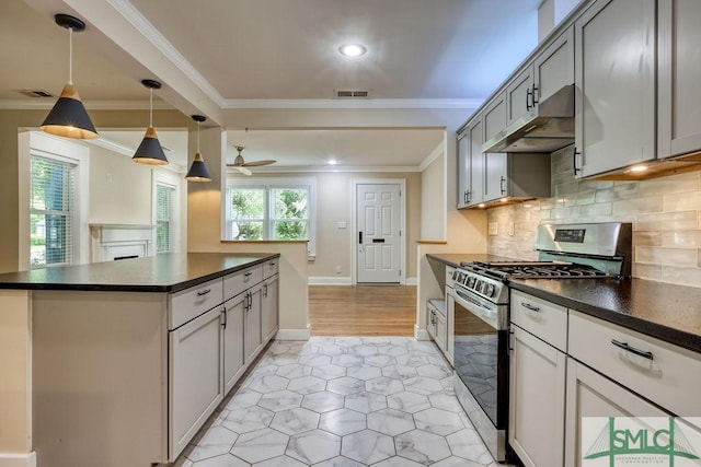 417 E 61st St, Savannah, GA 31405 - kitchen featuring stainless steel range with gas stovetop, under cabinet range hood, dark countertops, light tile patterned floors, and crown molding