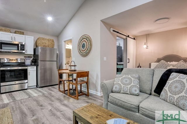 417 E 61st St, Savannah, GA 31405 - living room with a barn door, light wood-type flooring, lofted ceiling, and baseboards
