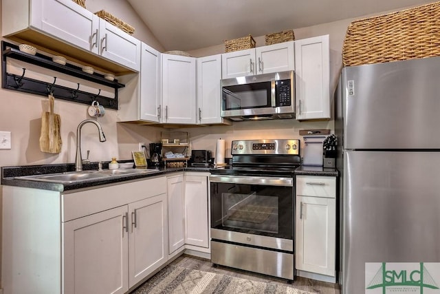 417 E 61st St, Savannah, GA 31405 - kitchen with appliances with stainless steel finishes, a sink, dark countertops, wood finished floors, and white cabinetry